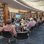 Students present to a group of new editors seated within the Auckland Museum library